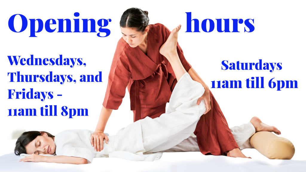 Female massaging female on floor mat in Thai lazy yoga position